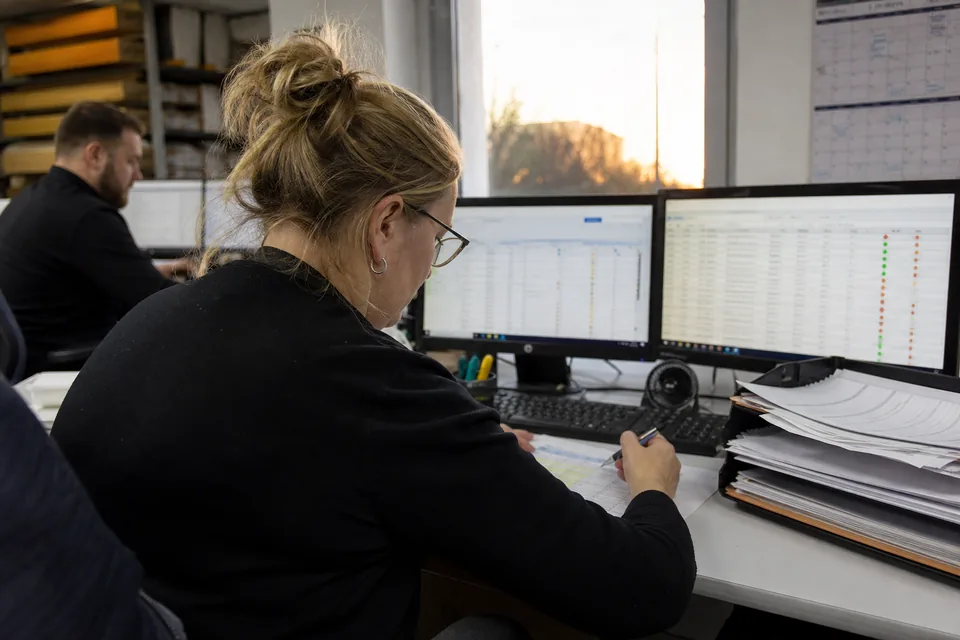 Specjalistka działu finansów porównuje listę kontrahentów ze statusami z wydrukiem przed zatwierdzeniem dostawy